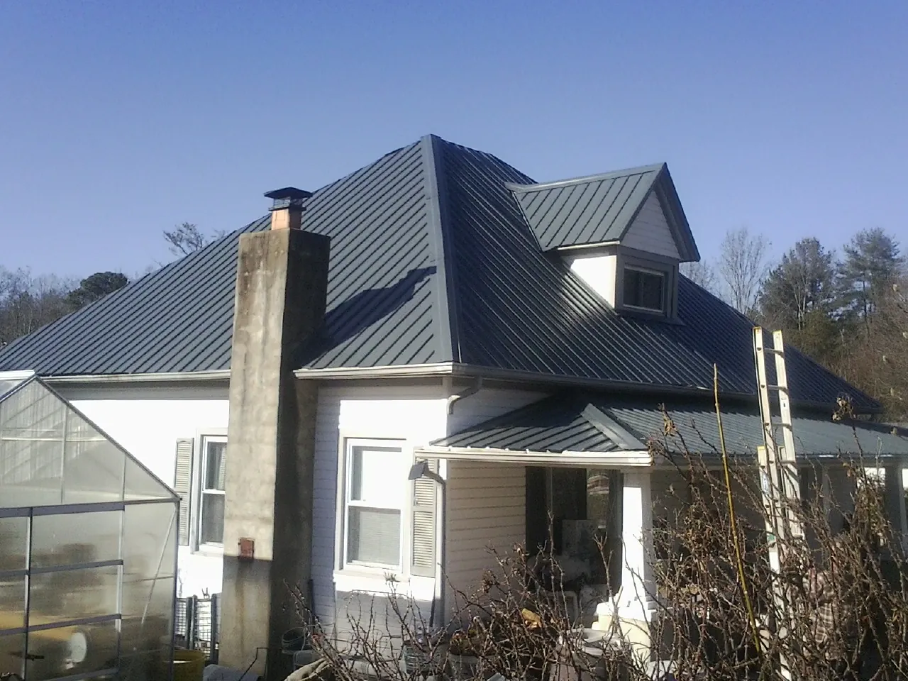 Dark blue standing seam metal roof on a white farmhouse with dormer — Slate & Tile Roof Repair by Roofing Brothers in West Haven