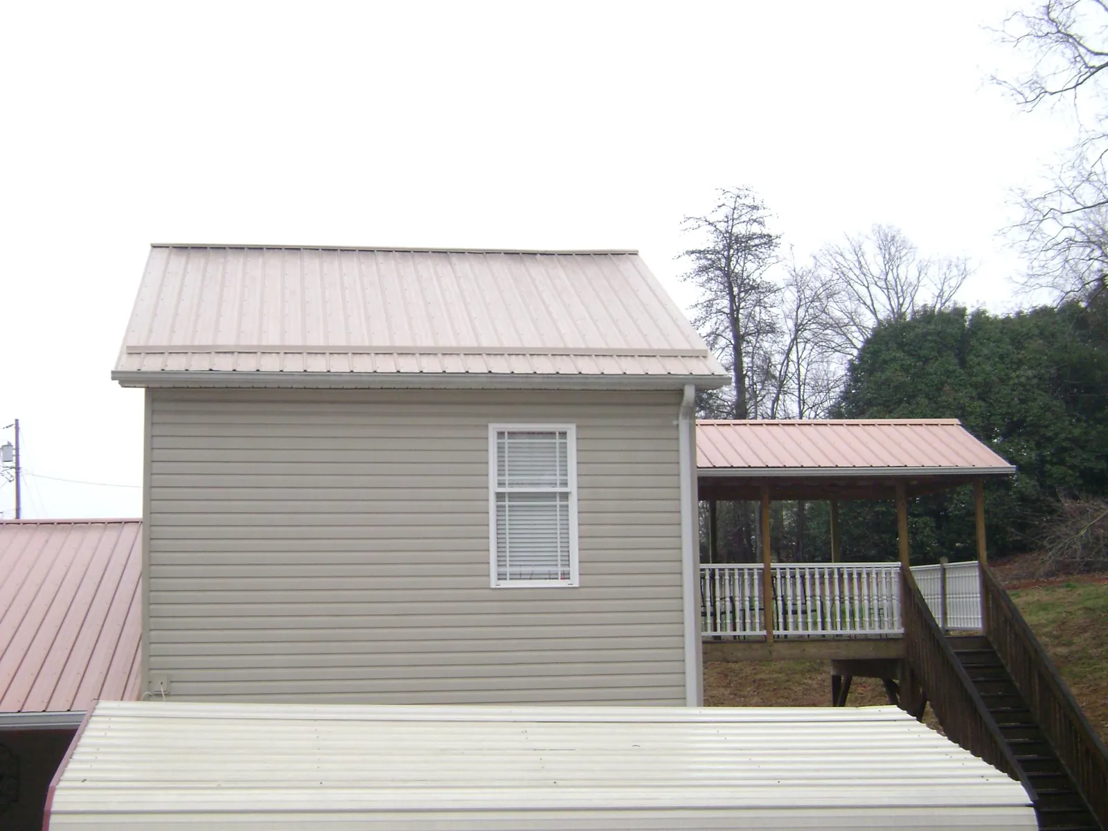 Tan metal roofs on a two story addition and attached porch, from a Roof Replacement job in West Haven