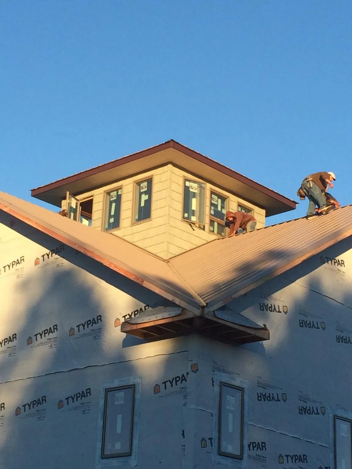 Roofers working around a rooftop cupola on a new metal roof at sunset — Roof Waterproofing in West Haven by Roofing Brothers